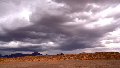 Fototapeta na wymiar Vista of a red sandstone formation in Death Valley under a dark stormy sky.