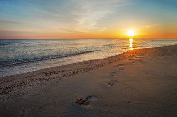 Dawn on the sea, footprints going along beach