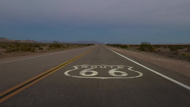Dusk driving over Route 66 pavement sign in the Mojave desert in Southern California.
