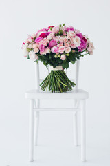 A beautiful  floral bouquet sitting isolated on a white  chair.