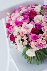 Large  bouquet of roses on  white chair.