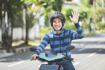 man riding a motorbike and waving hand