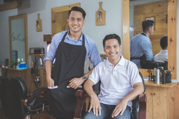 man getting haircut by hairdresser at barbershop