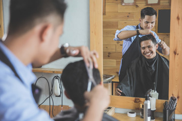 barber making haircut of attractive man in barbershop