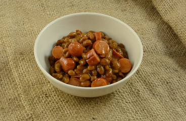 Sliced turkey hot dog frankfurters and baked beans in white bowl