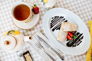 Pancakes with chocolate, strawberry and mint, with cup of tee
