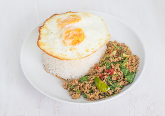 Steamed rice topped with fried egg and fried pork with basil leaves