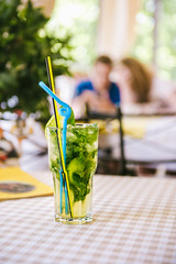 Mojito with straws and lemon wedge in high glass