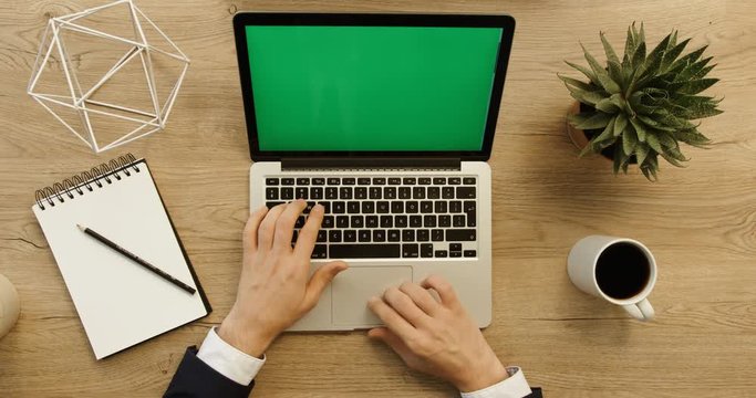 Business man working and writing in laptop with green screen on office desk background. Hands top view. Slow motion. red epic