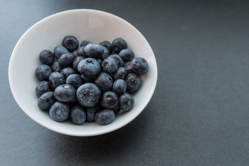 Natural looking blueberries in white cup. Selective focus.