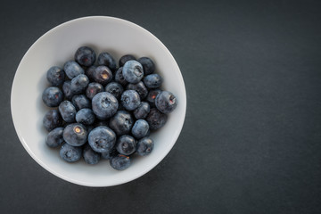 Natural looking blueberries in white cup. Selective focus.