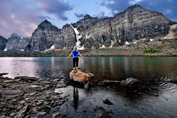 Young woman meditating by lake in Valley of Ten Peaks. Eifel Lake in Banff National Park. Rocky Mountains.  British Columbia. Canada.