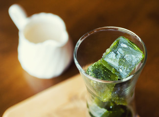 matcha green tea ice cubes with fresh milk on wooden table