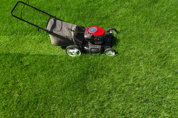 Fototapeta na wymiar Lawn mower in the garden on green grass photographed from above