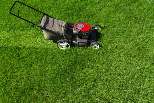 Lawn Mower In The Garden On Green Grass Photographed From Above