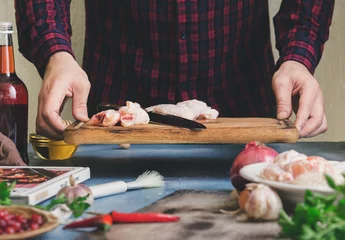 Foto op Canvas Man prepares chicken wings with cranberry sauce in home kitchen © kucherav