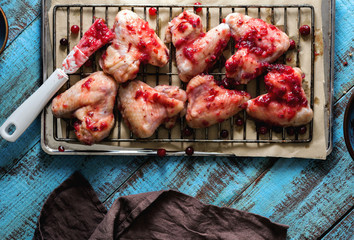 Naklejka premium Close-up raw chicken wings in cranberry sauce on baking sheet