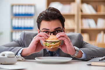 Hungry funny businessman eating junk food sandwich