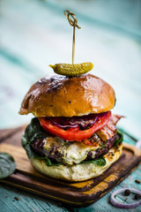 Tasty burger with beef with spinach and blue cheese served on a small board on a wooden background.