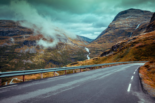 Driving a car on mountain road. Road among mountains with dramatic stormy cloudy sky. Landscape.  Beautiful nature Norway. 
