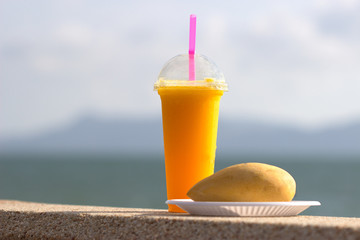 Натуральный сок из манго на фоне моря и гор