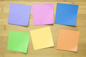 Multicolored paper sticker note on wooden board