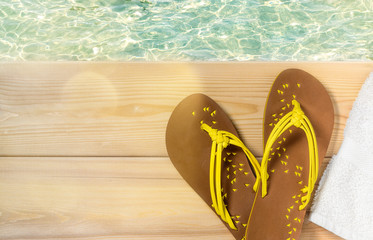 Summer beach vacation, flip flops and towel on wood deck