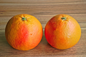Closeup of two red grapefruits on a wooden table