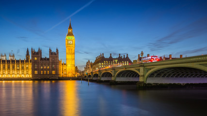 Fototapeta na wymiar London, England - The Big Ben Clock Tower and Houses of Parliament with iconic red double-decker buses at city of westminster by night