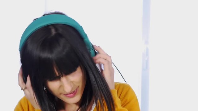 Young brunette woman with  headphones listening music, slow motion