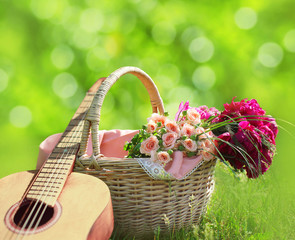 Fototapeta na wymiar Romance, love, valentine's day concept - wicker basket with bouquet of flowers, guitar on the grass. Spring fresh sunny background
