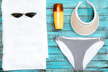 top view of towel, swimming pants, sunglasses and sun cream on table