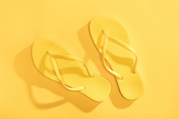 Close-up top view of comfortable yellow flip-flops on yellow background