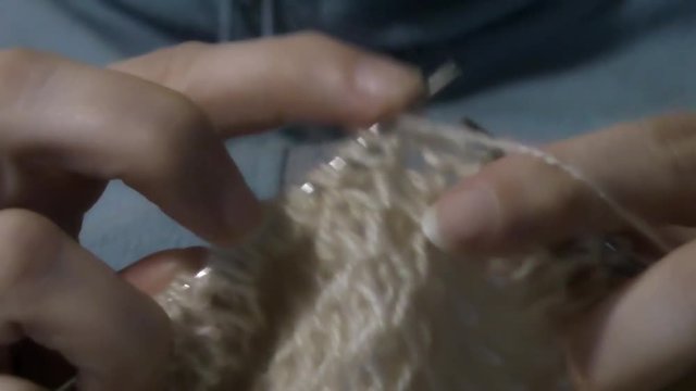 Female hands knitting needles knitting sweater of white wool yarn