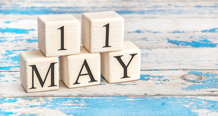 May 11th. Wooden cubes with date of 11 May on old blue wooden background.