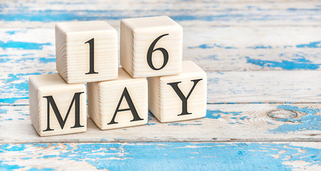 May 16th. Wooden cubes with date of 16 May on old blue wooden background.