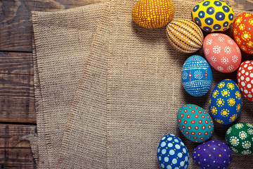 Colorful easter eggs on on sackcloth with space on wooden background