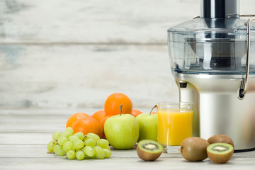 Modern electric juicer, various fruit and glass of freshly made juice, healthy lifestyle concept - obrazy, fototapety, plakaty