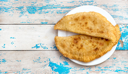 Plate with chebureks on the old wooden table. Top view.