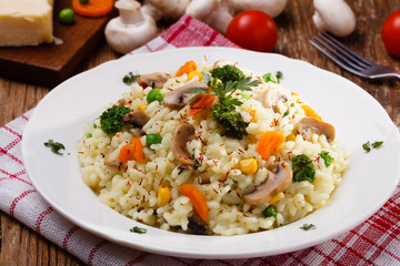 Classic Risotto with mushrooms and vegetables served on a white plate.