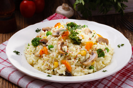 Classic Risotto with mushrooms and vegetables served on a white plate.