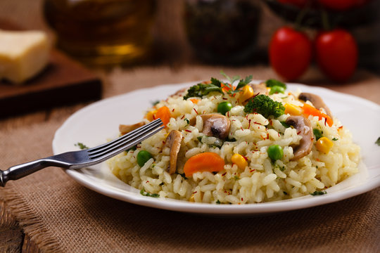 Classic Risotto with mushrooms and vegetables served on a white plate.
