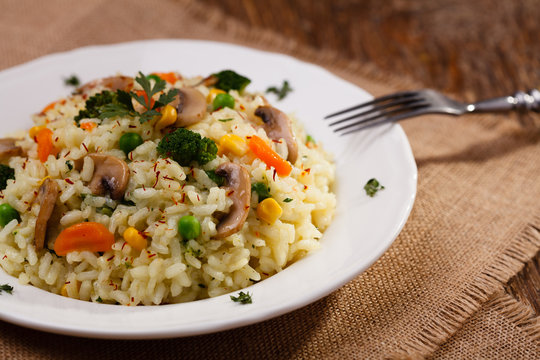 Classic Risotto with mushrooms and vegetables served on a white plate.