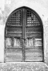 Fototapeta na wymiar Wooden door in an old Italian house, copy-space, black and white.
