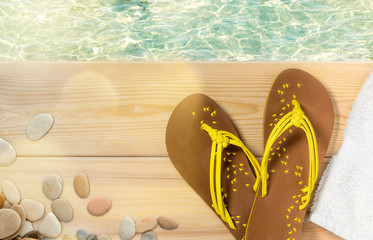 Summer beach vacation, flip flops, towel and sea pebbles on wood deck