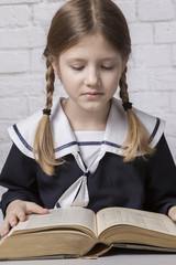 dziewczynka z książką w mundurku szkolnym - obrazy, fototapety, plakaty