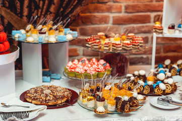 blue white sweets on gilded paper on the wedding candybar. Brick wall on a background