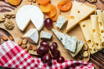 Assortment of cheese with fruits and grapes on a wooden table