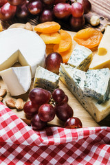 Assortment of cheese with fruits and grapes on a wooden table