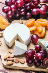 Assortment of cheese with fruits and grapes on a wooden table